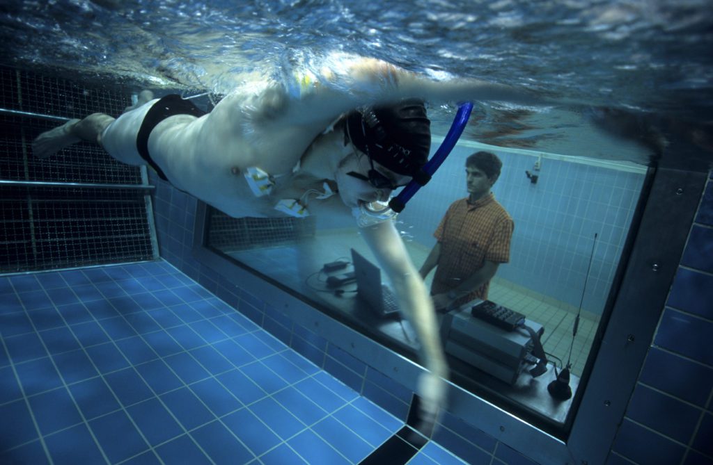 Athlete rigged for electromyography swimming in flow channel, Berlin, Germany